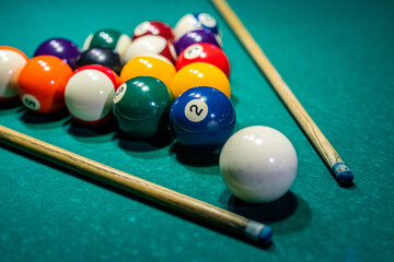 female hands in deftly holding a cue and trying to drive a billiard layer into the hole.
