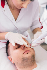 Cosmetologist doing hydrafacial treatment on man face