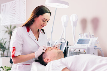 Cosmetologist doing hydrafacial treatment on man face