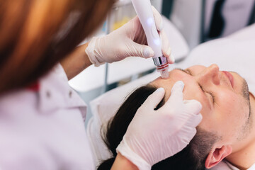 Obraz na płótnie Canvas Cosmetologist doing hydrafacial treatment on man face
