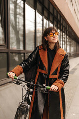 Fototapeta na wymiar Full view of smiling woman in sunglasses with bike look at camera 