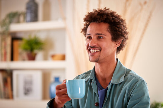 Smiling Man Relaxing At Home Sitting At Table With Hot Drink