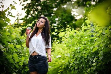 Young beautiful smiling woman   in a Vineyard with a glass of  rose wine during the summer vacation. Wine tourism