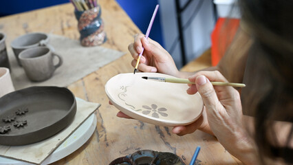 A female hands making a ceramic plate, painting and drawing on ceramic plate