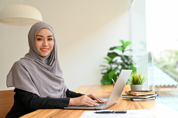 Portrait of a beautiful muslim businesswoman with hijab using laptop computer