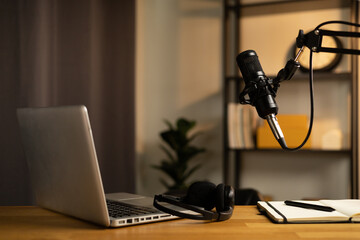 Desk of host streaming radio podcast at home broadcast studio.Such as laptop condenser microphone and headphone on table. Recording host streaming radio podcast interview conversation at home