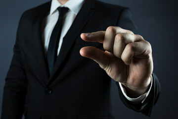 A businessman on a black background shows a gesture with two fingers, small, holding. Works on an...