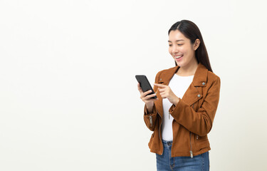 Fototapeta premium Pretty young asian woman using smartphone standing on isolated white background. She texting on cell phone. Dressing with jacket and jean.