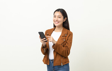 Pretty young asian woman using smartphone standing on isolated white background. She texting on cell phone. Dressing with jacket and jean.