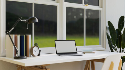 Minimal home working desk against the window with portable laptop mockup and decor