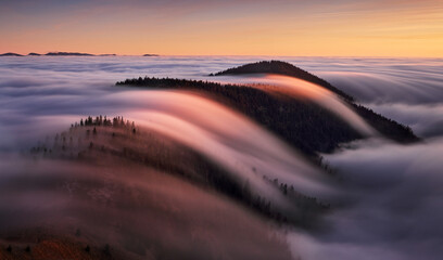 Beautiful landscape, misty fog on mountain slopes, abstract view over clouds.