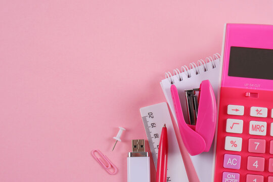 Notepad,calculator,pen,ruler,stapler, flash drive,paper clips in pink and white tones.Goods for businessmen, schoolchildren, students, teachers.Planning,sale of office supplies for the academic year