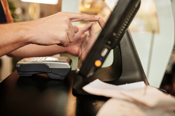 Coffreeshop waiter sending order to kitchen via cash register terminal