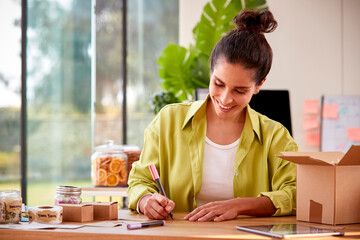 Woman Running Online Business From Home Packing And Labelling Boutique Candles Ready For Shipping