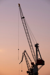 A silhouette of an old shipyard crane against the sunset