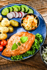 Pork cutlet coated with breadcrumbs with potatoes and salads