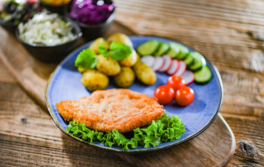 Pork cutlet coated with breadcrumbs with potatoes and salads