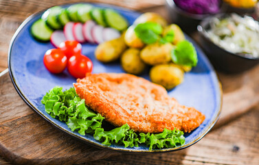 Pork cutlet coated with breadcrumbs with potatoes and salads