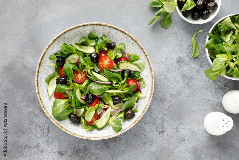 Wall mural Salad with corn salad, cucumber, olives and tomato, top view