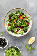 Salad with corn salad, cucumber, olives and tomato, top view