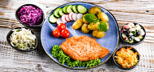 Pork cutlet coated with breadcrumbs with potatoes and salads
