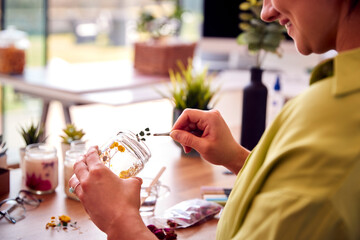 Close Up Of Woman Making Boutique Flower Candles To Sell Online Working From Home