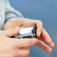 A man holds in his hands and looks through the footage on an action camera