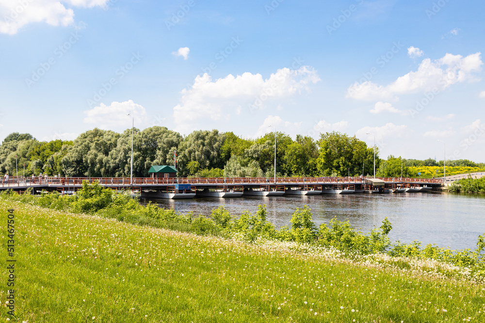 Poster view of Bobrenevskiy pedestrian movable pontoon bridge on Moskva River in Kolomna city on sunny summer day