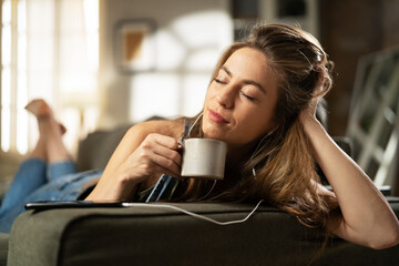 Young woman at home. Beautiful girl listening the music while drinking coffee