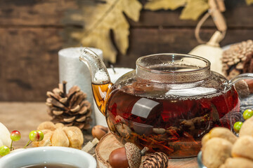 Autumn tea concept. Cookies with pumpkin puree, black tea in a glass teapot, fall decor