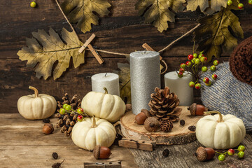 Fototapeta na wymiar Autumn composition with traditional decor. White pumpkins, candles, fall leaves, acorns, cones