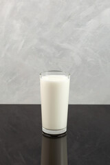 Buttermilk or Kefir in tall clear glass. Fermented milk ayran. Milk diet for weight loss. Grey background, copy space