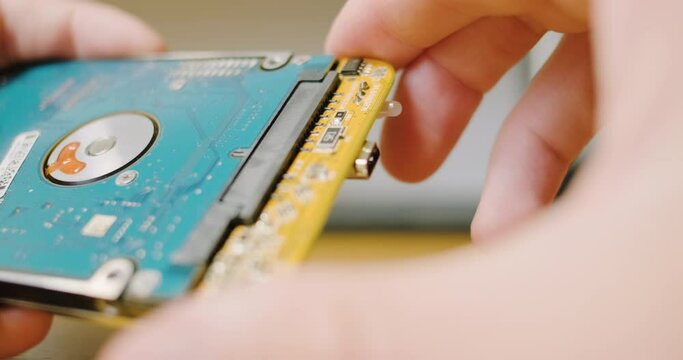 Man's hand disconnect sata control board hard drive for an external drive pocket. Close-up. Concept is to disassemble, break contact.