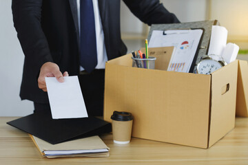 Resignation Concept . Businessman sending a resignation letter to the boss and carrying a cardboard box. Include resignation, job placement, Quitting a job, and The big quit. The great Resignation. - obrazy, fototapety, plakaty