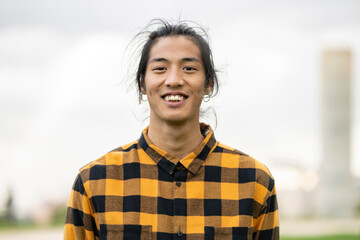 portrait of a young asian filipino man smiling at camera outdoors - obrazy, fototapety, plakaty