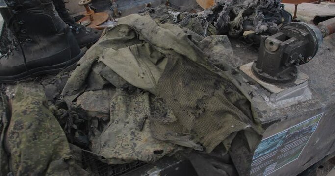 Close-up detailed tracking shot of the armor of a burnt-out Russian airborne combat vehicle. Exibition in Kyiv on Sophia Square The uniform of the killed soldier  destroyed by the explosion