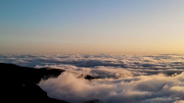 Drone showing people on a rock above the clouds during sunrise in Madeira