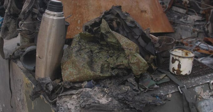 Close-up detailed tracking shot of the armor of a burnt-out Russian tank. Exibition in Kyiv on Sophia Square The uniform of killed soldier  destroyed by explosion thermos, mugs and personal items