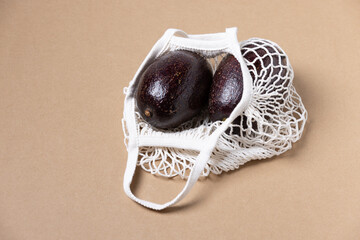 ECO friendly mesh grocery shopping bag with avocado on brown background , top view. Plastic free and Zero Waste lifestyle concept