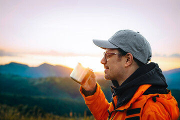 Mam drinking coffee on mountain at sunrise