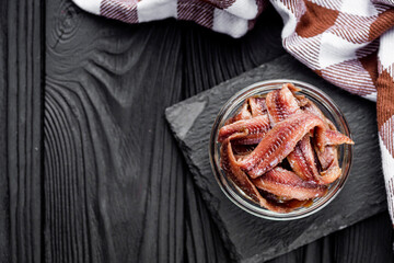 canned anchovy fillet on a black wooden rustic background - obrazy, fototapety, plakaty