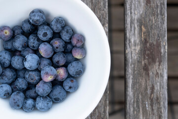 Blueberry in a white plate on  old wooden table