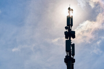 Telecommunication tower of 5G cellular. LTE radio network communication equipment with wireless modules and smart antennas mounted on metal pillar on clouds sky background. Macro base station.