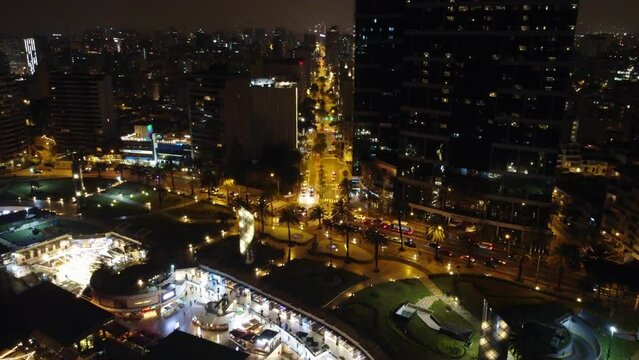 Drone video of larcomar shopping center and a street in Miraflores Lima, Peru "Avenida Jose Larco". Shot during night time flying slowly forward. City lights can be seen far into the horizon.