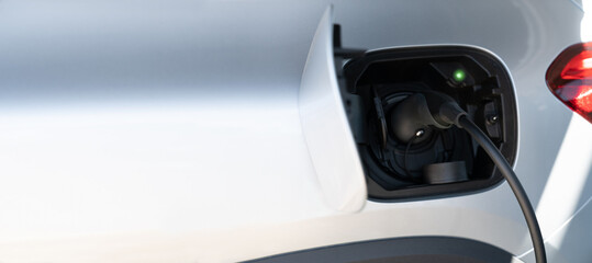 Close up of electric car inlet with a connected charging cable. Copy space