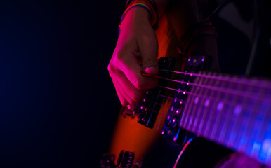 girl playing guitar with concert lights and black background