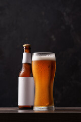 Bottle and glass of beer on black background.