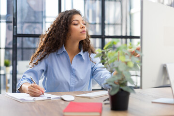 Beautiful business woman is examining documents while sitting in the office