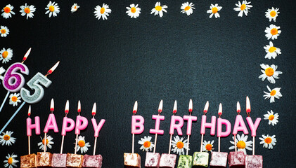 Happy birthday background with number   65. Copy space. Pink happy birthday candles on a black...