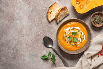Pumpkin cream soup on a rustic brown background. Warming winter or autumn soup. Top view, flat lay.
